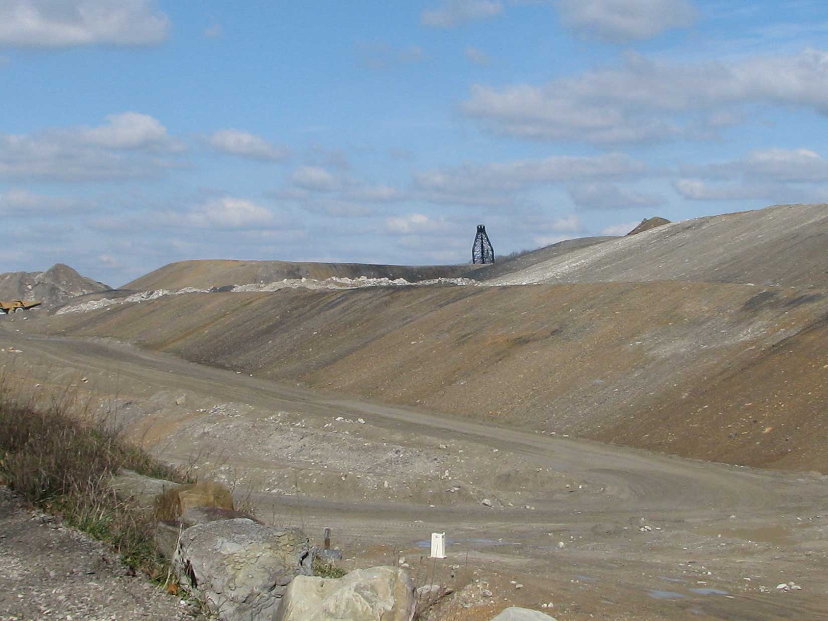 Large open quarry landscape with dirt roads, mining equipment, and barren hills