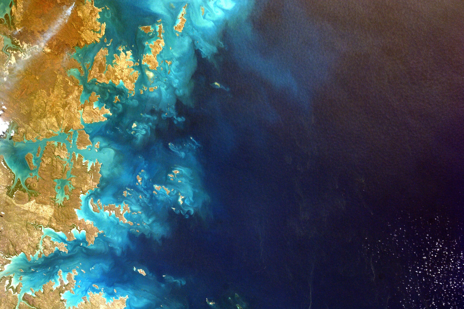 Satellite-style view of turquoise islands and deep ocean waters with swirling patterns