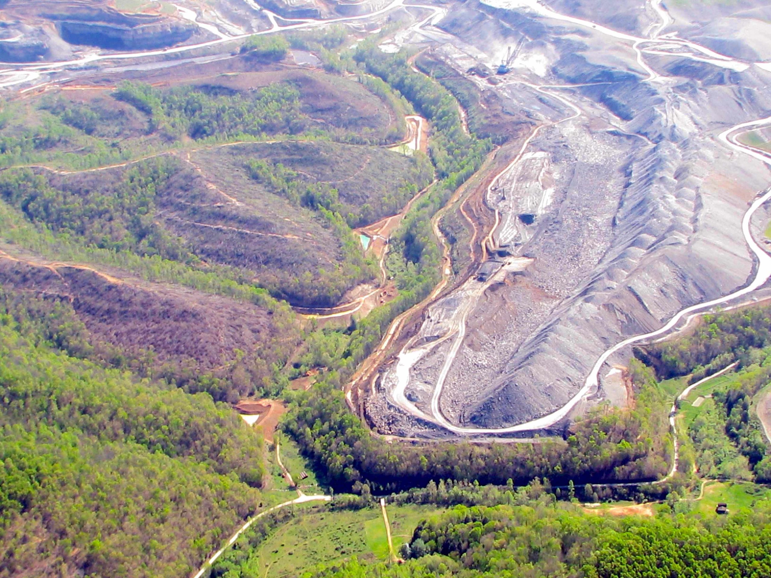 Aerial view of mining site with winding roads, cleared land, and forest edges