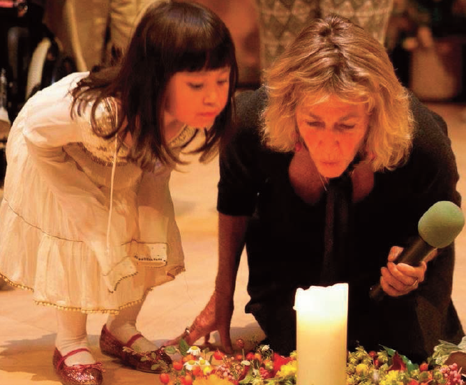 Elder, Gigi Coyle, along with Findhorn community child, Aayana Ito, blow out the Summit candle with a blessing for the children.